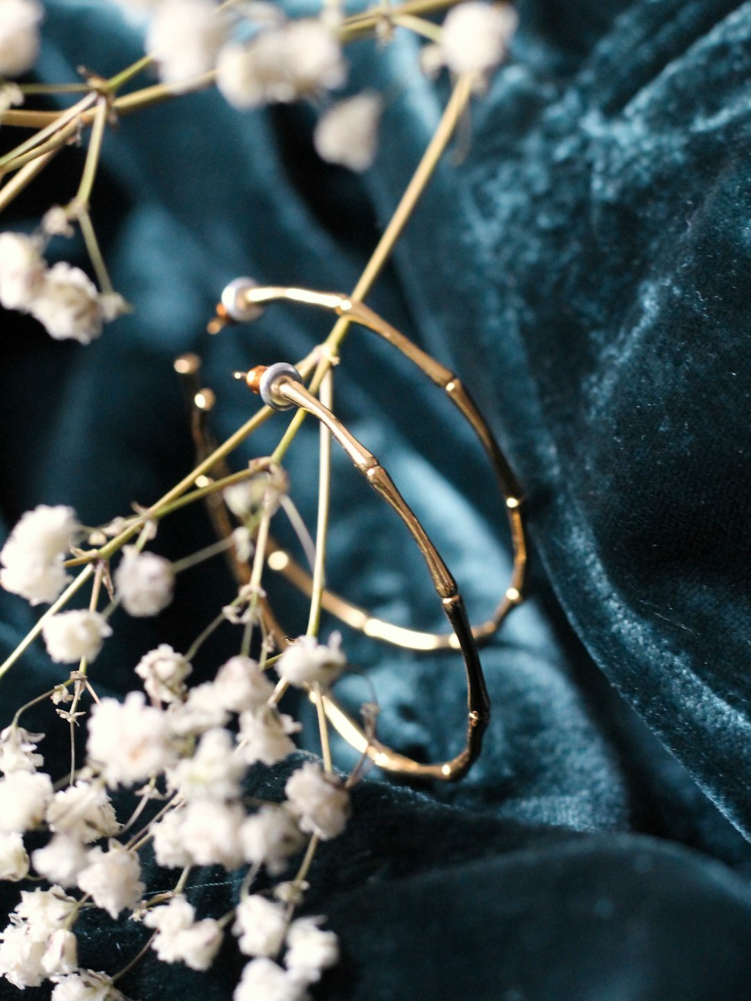 Close-up of a gold bracelet resting on dark silk fabric